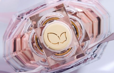 Refined pink and gold perfume bottle with butterfly logo, highlighting elegance and luxury.