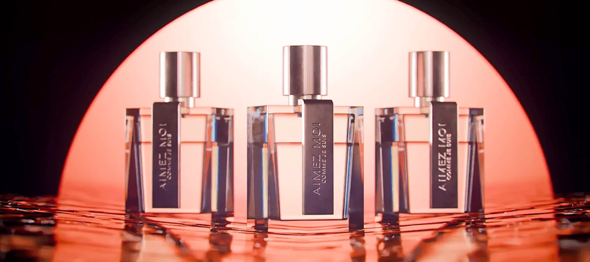 Refined perfume bottles with modern design on a reflective surface under warm lighting.