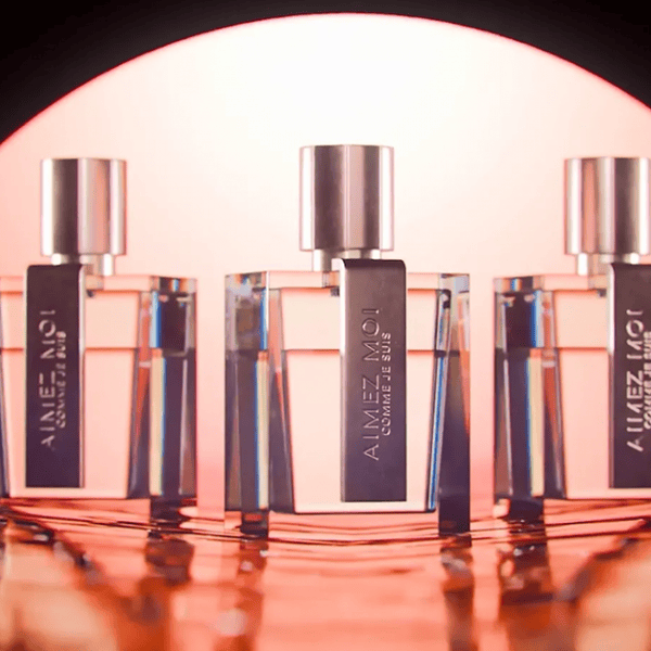 Refined perfume bottles with modern design on a reflective surface under warm lighting.